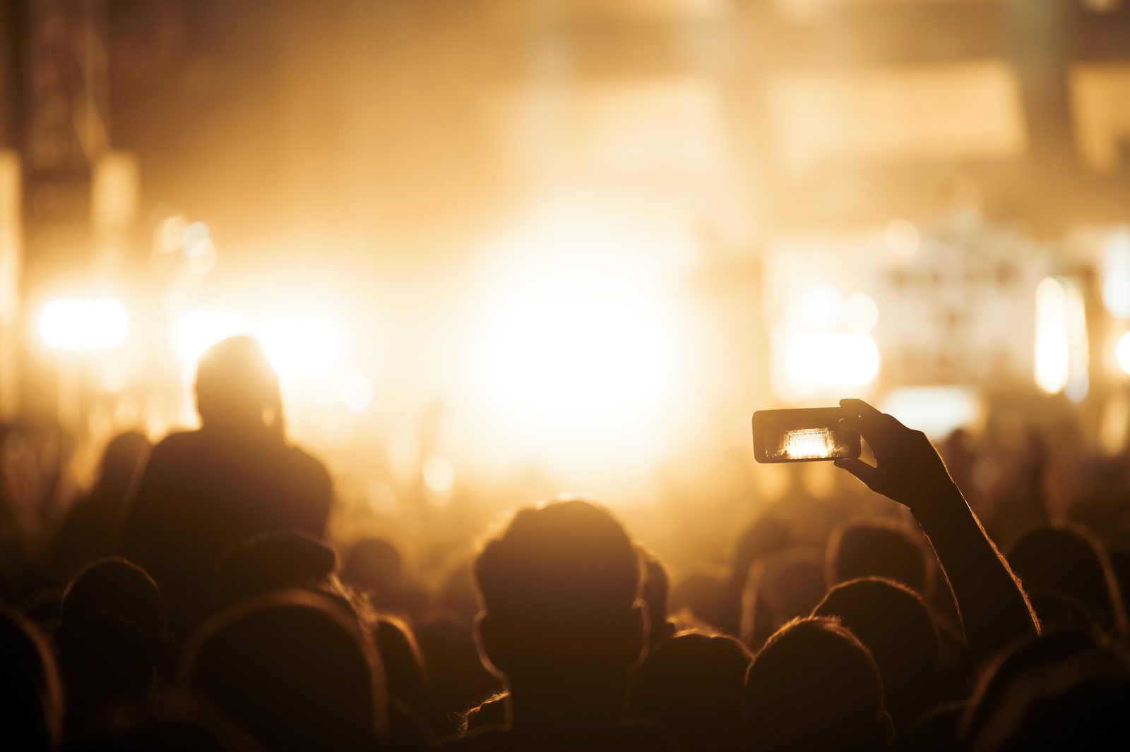 Crowd at a festival with stage lights at golden hour