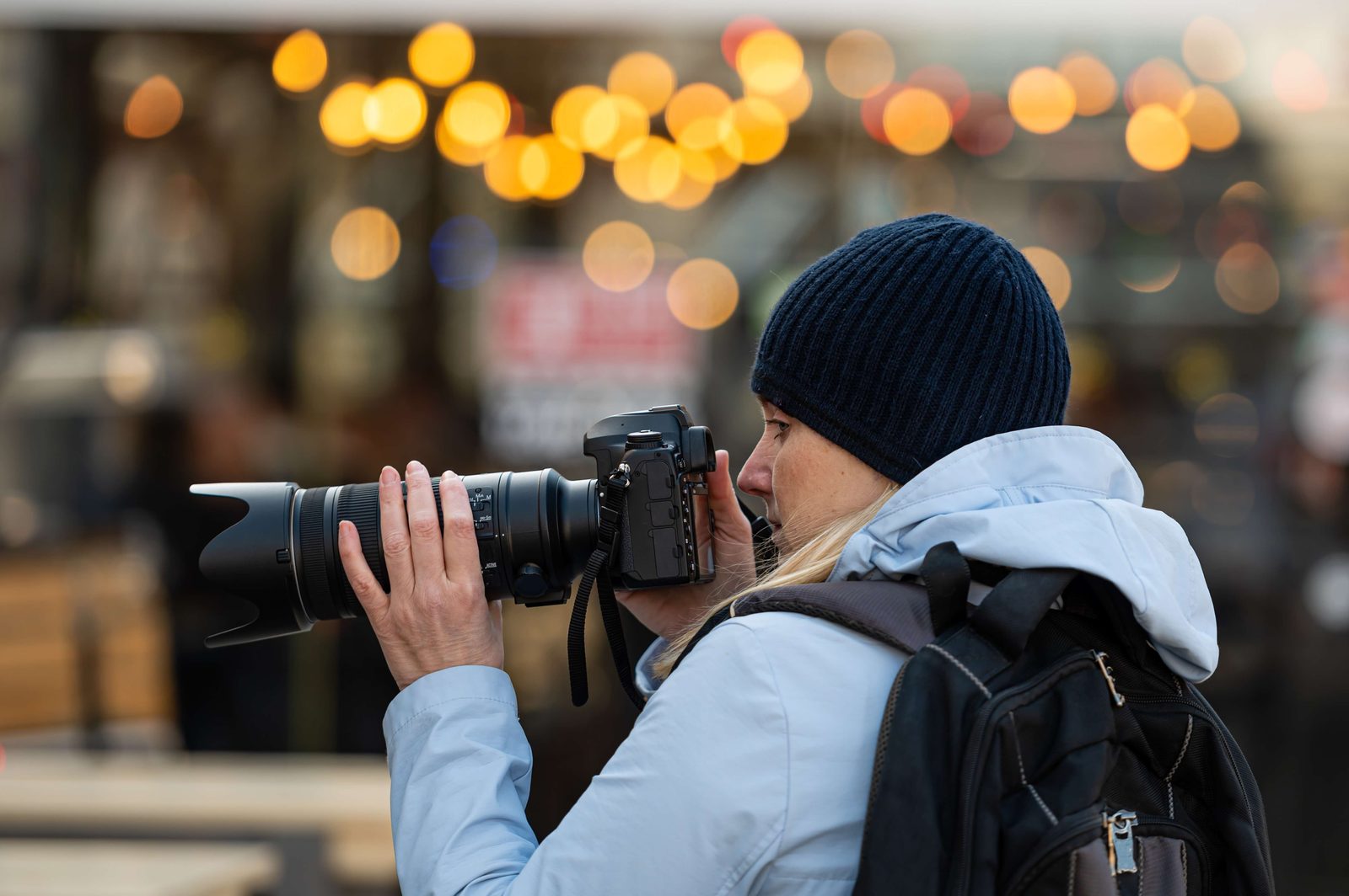 Photographer shooting at an event with festival lights behind